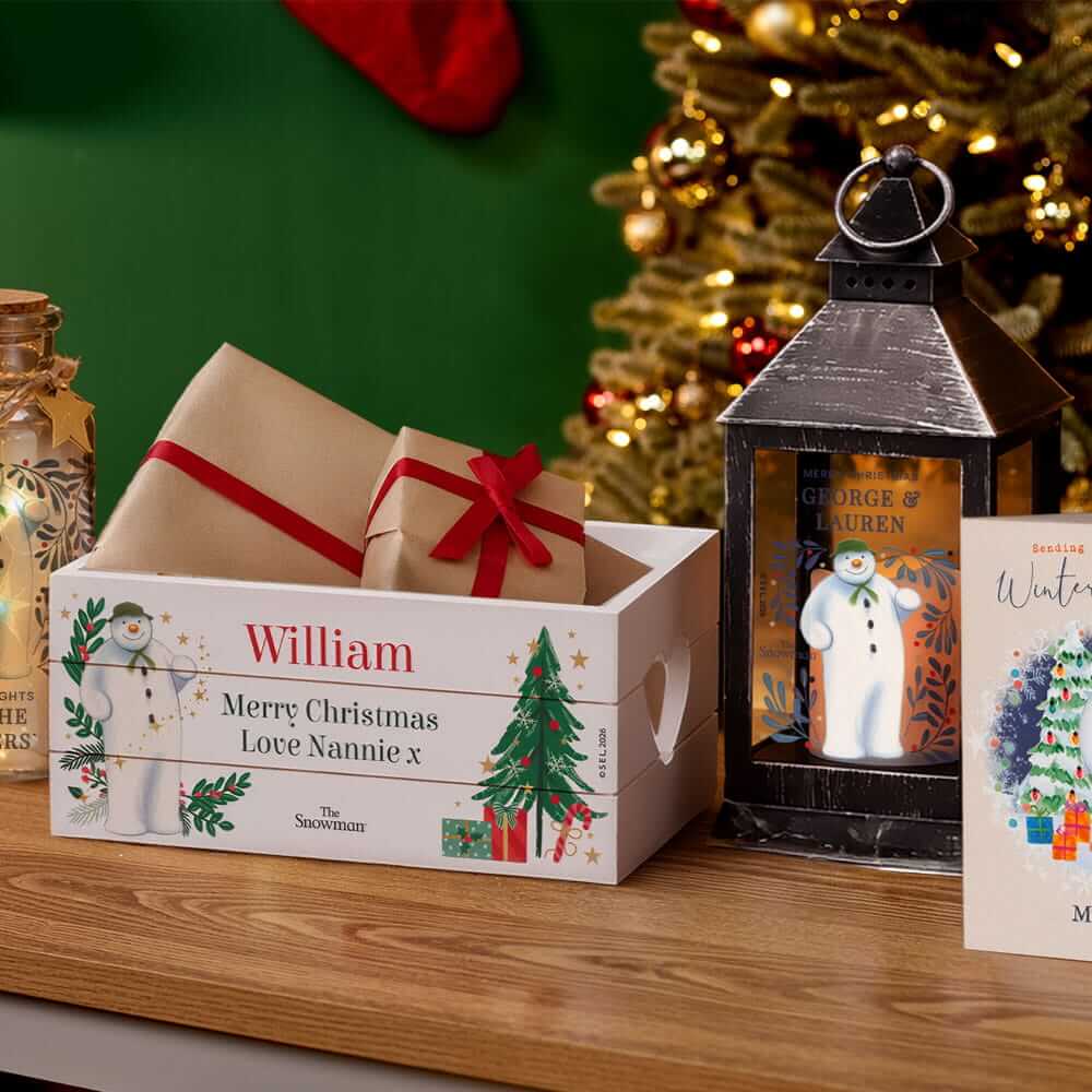 Personalised Christmas Eve box, festive lantern and Christmas card displayed on a wooden table in front of a decorated Christmas tree. Personalised Christmas Eve box, festive lantern and Christmas card displayed on a wooden table in front of a decorated Christmas tree.